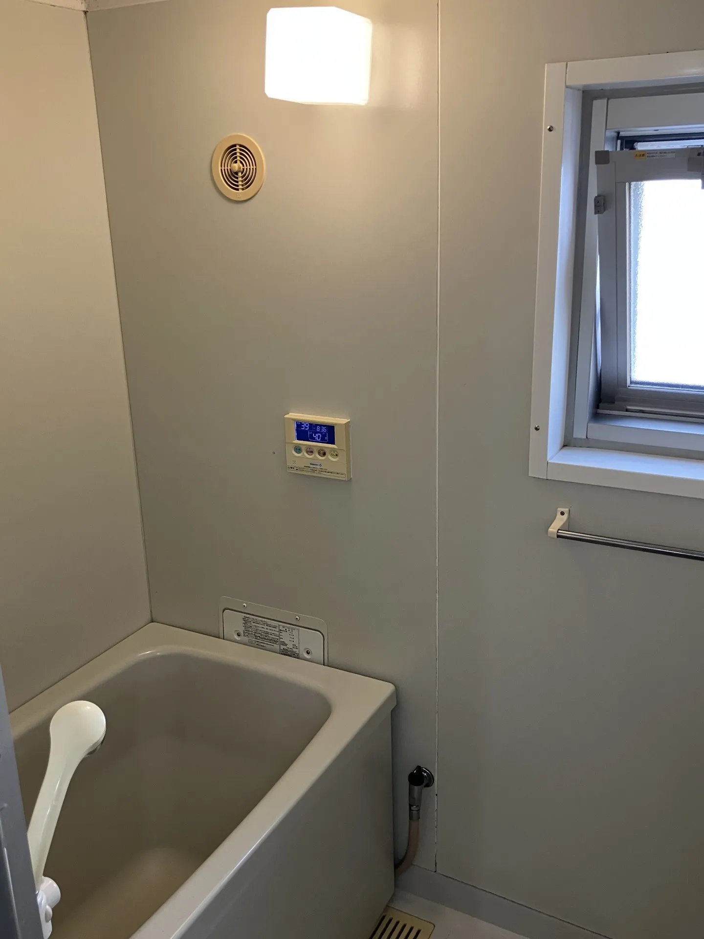 リフォーム前の浴室。浴槽の隣に設置されたパックイン給湯器（壁貫通型）の様子